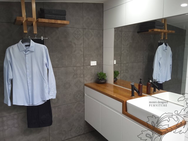 Timber vanity with white sink and clothes hung up